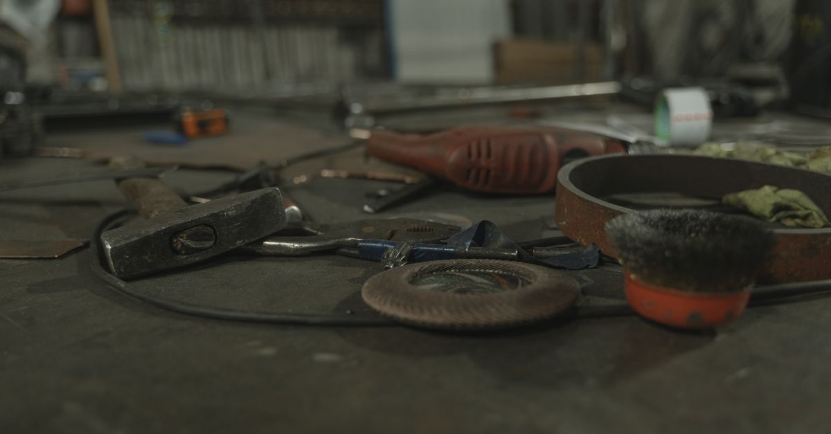 A selection of various tools scattered on a workbench in an industrial setting.